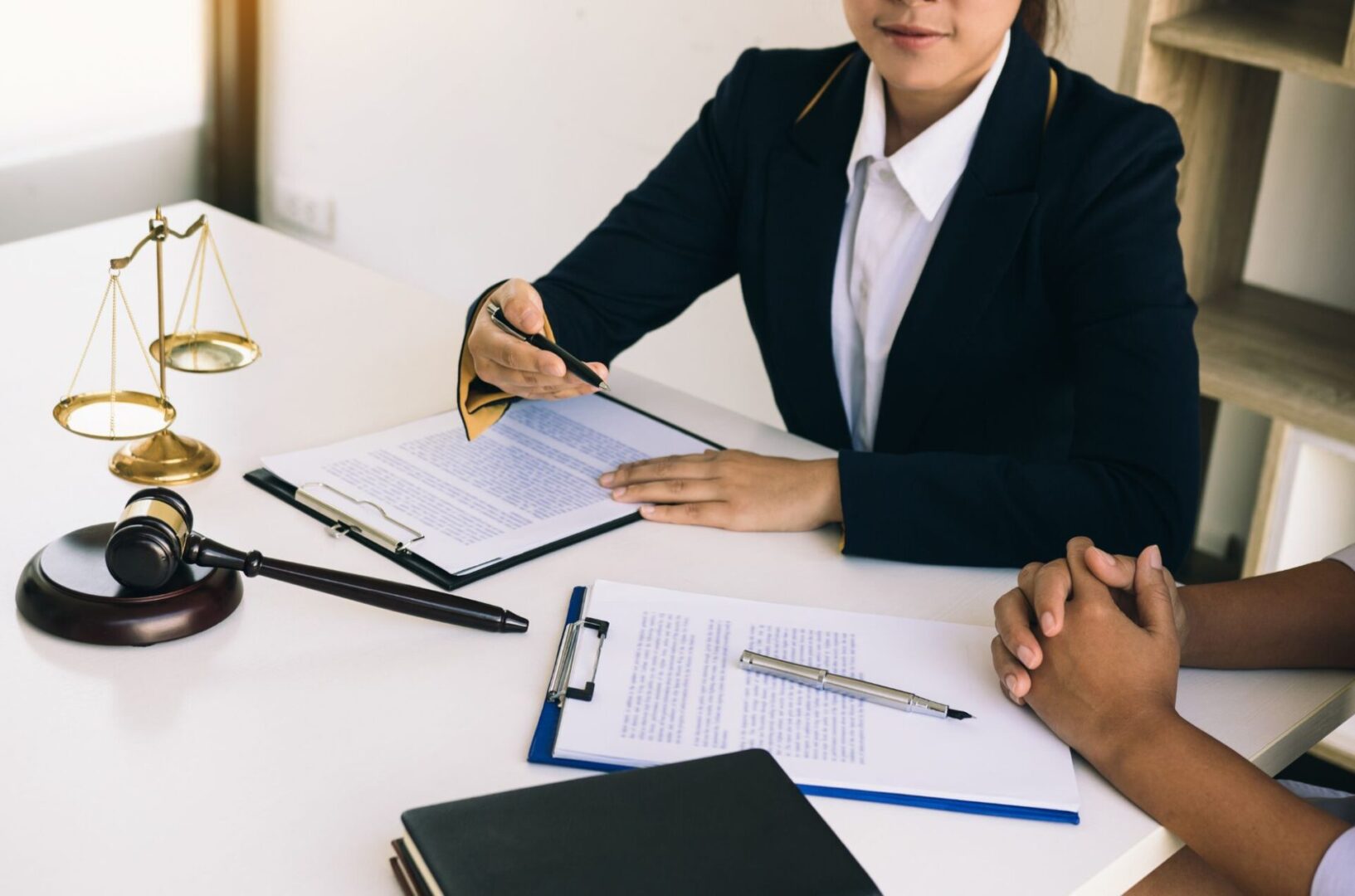 A woman in black jacket holding papers near table.