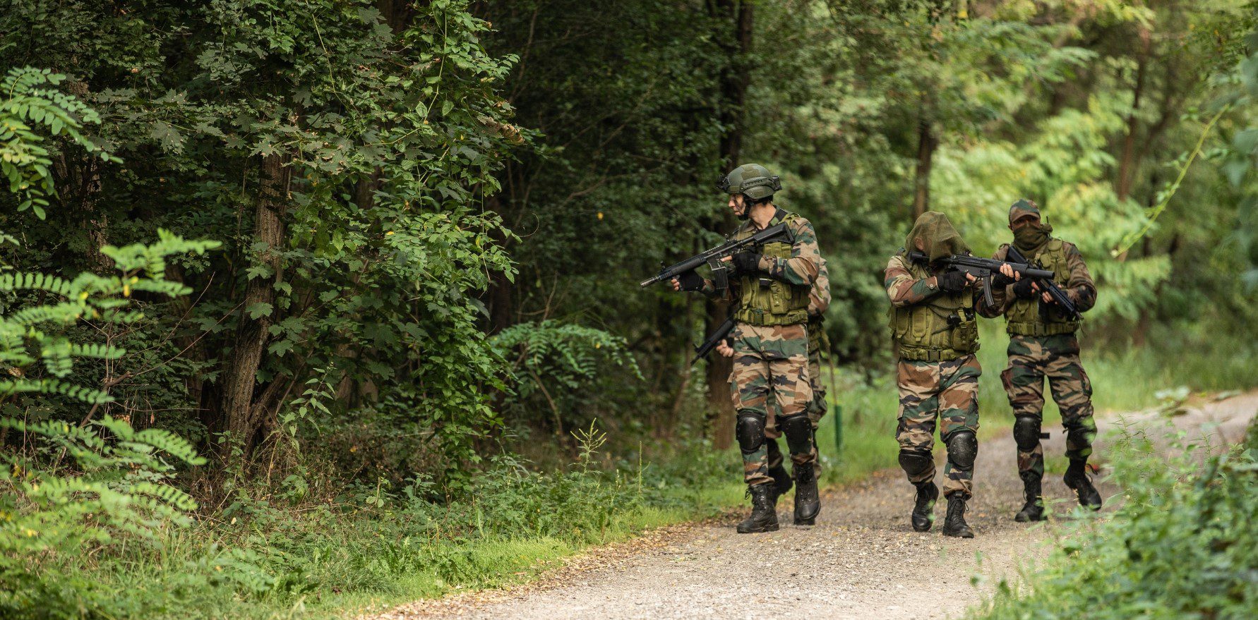 Two soldiers are walking down a path in the woods.